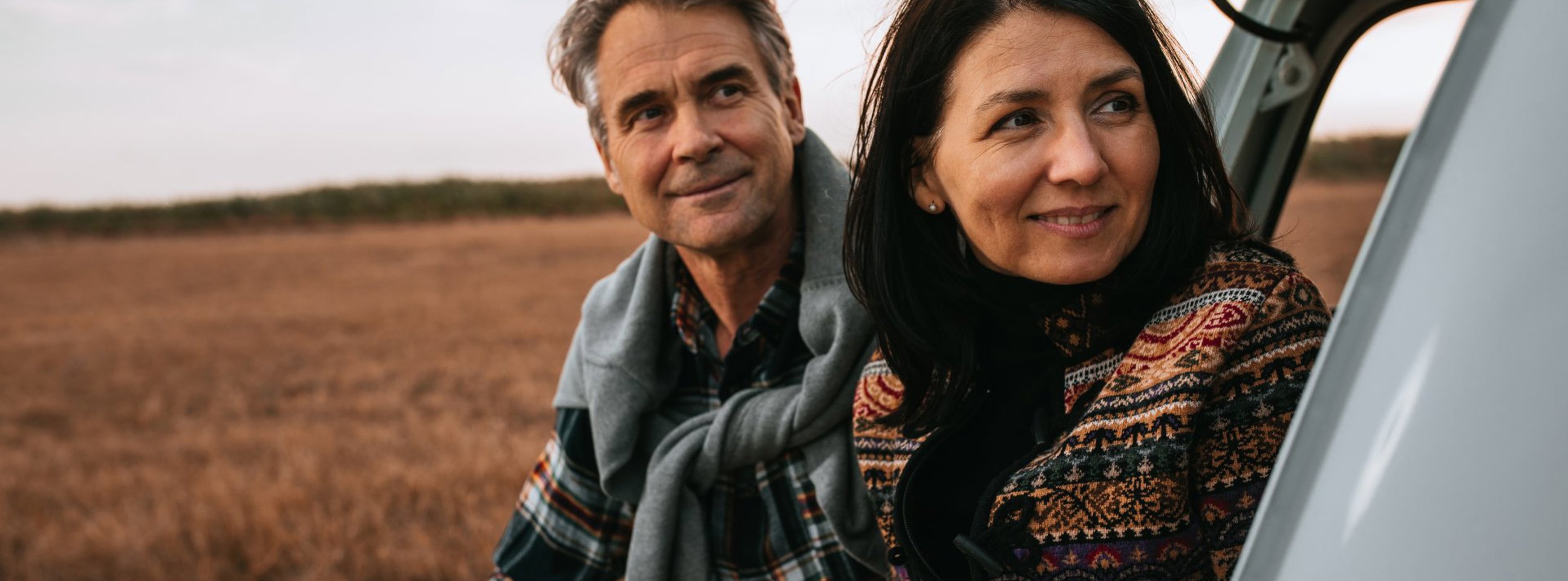 Et midaldrende par sidder i bagagerummet på deres bil og nyder udsigten