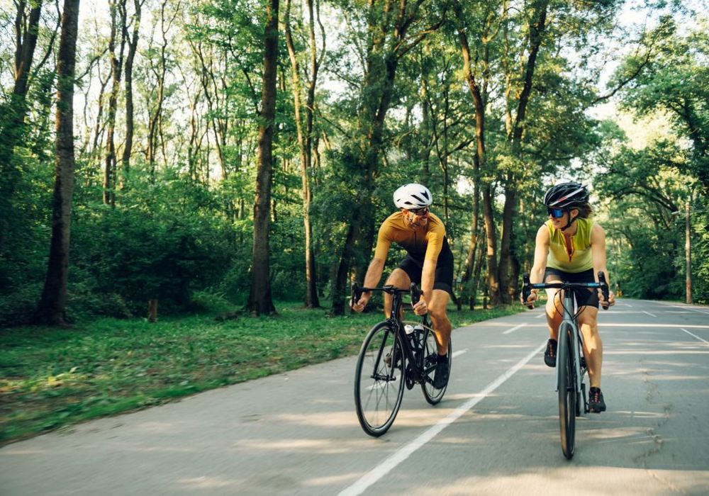 To cykelryttere i fuldt udstyr - en mand og en kvinde - cykler på en landevej