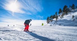 Mand der står på ski i solskin.