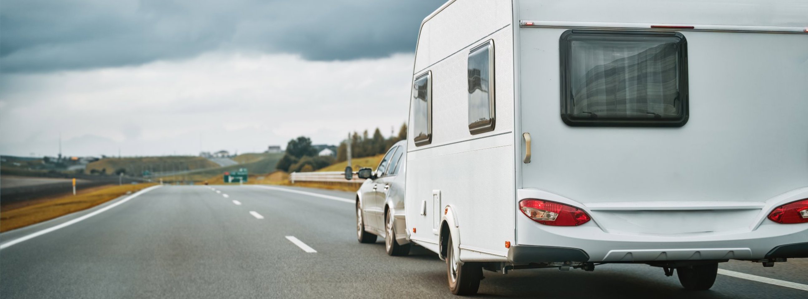 Bil med campingvogn kører på motorvejen