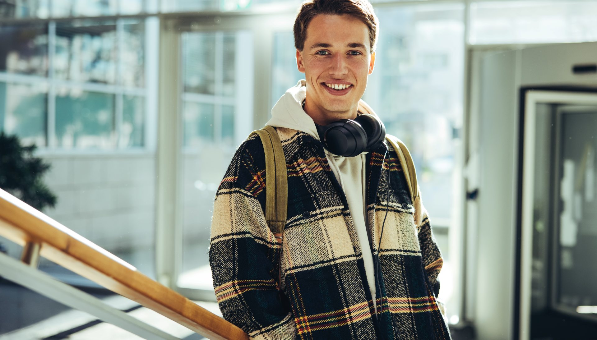 Ung mand står med hørebøffer rundt om halsen