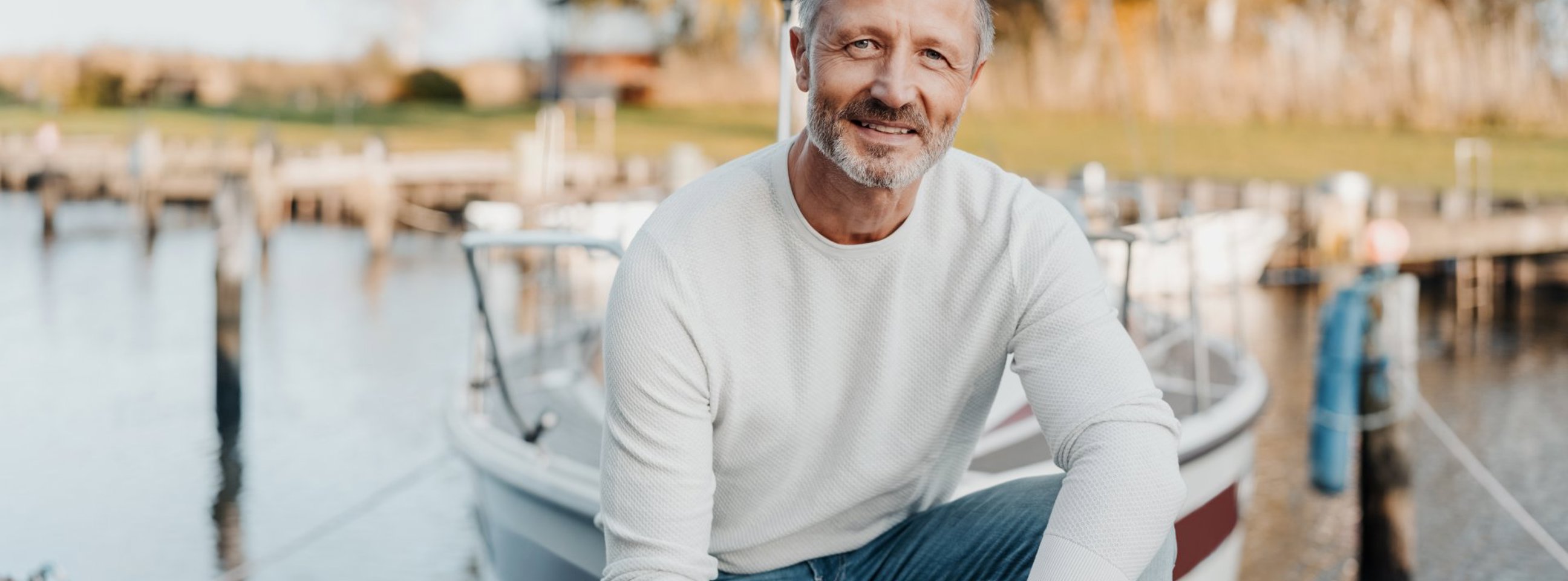 Mand sidder på en bådebro foran en fortøjret båd