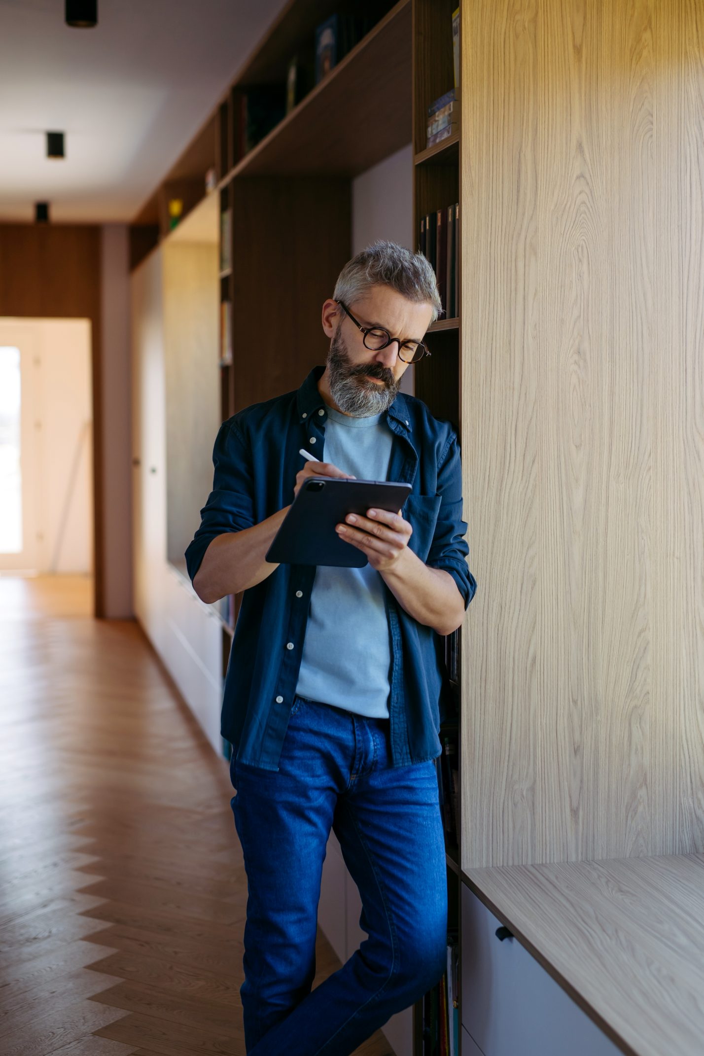 En mand med briller står og kigger på sin iPad