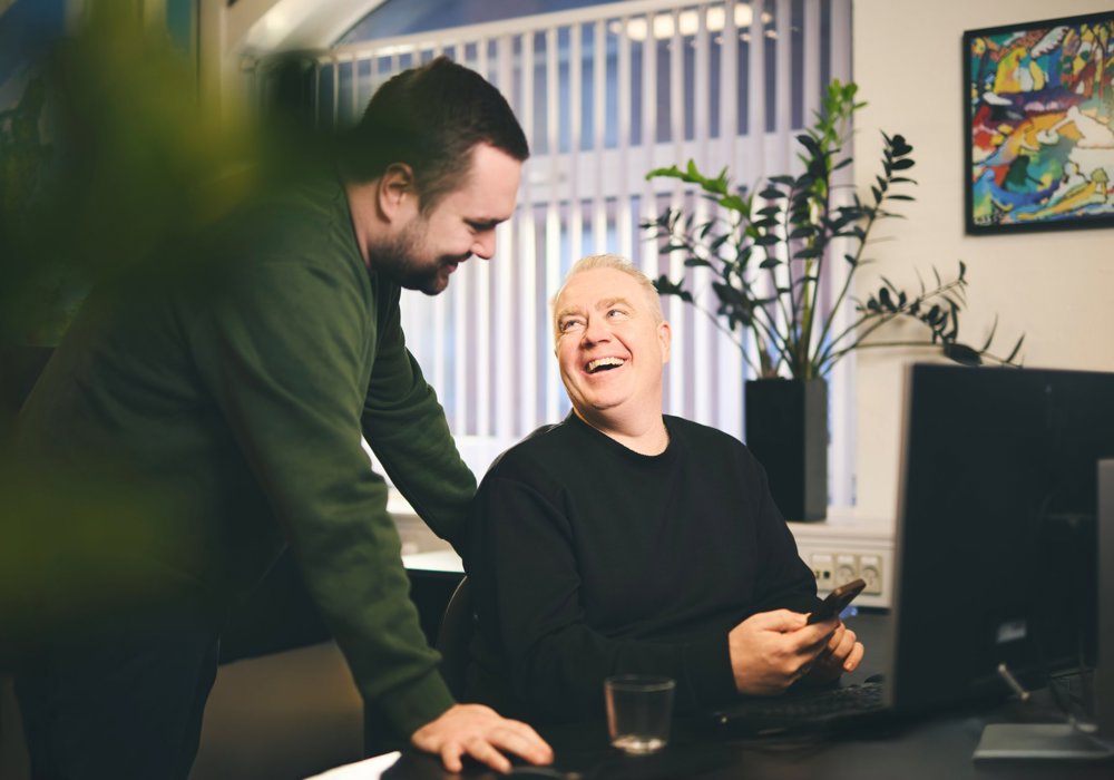 To mandlige forsikringsrådgivere snakker sammen ved et skrivebord