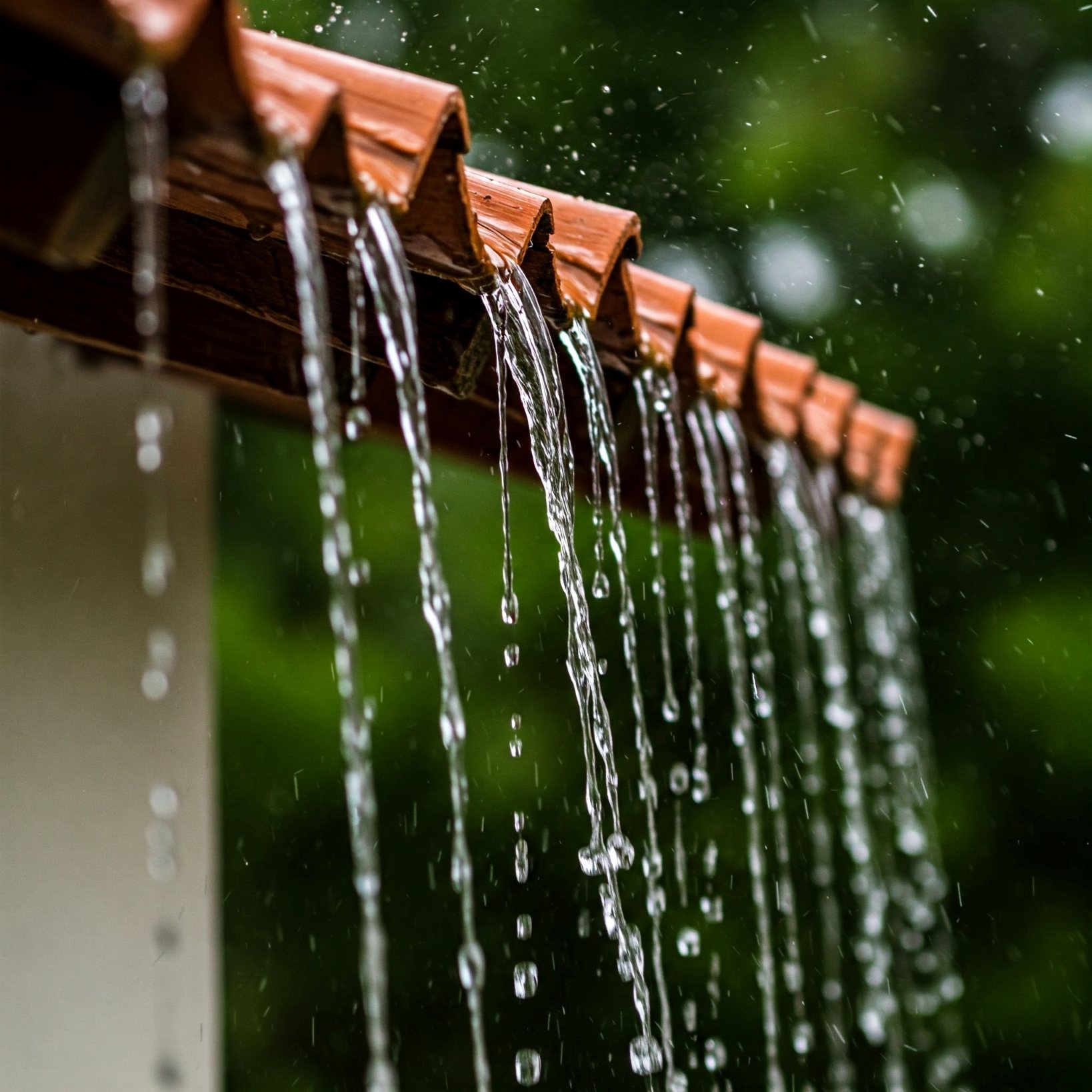 Nærbillede af regn, der løber ned fra et rødt tag