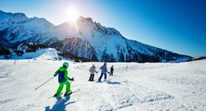 Flere der står på ski i skoleskin imellem bjerge. 