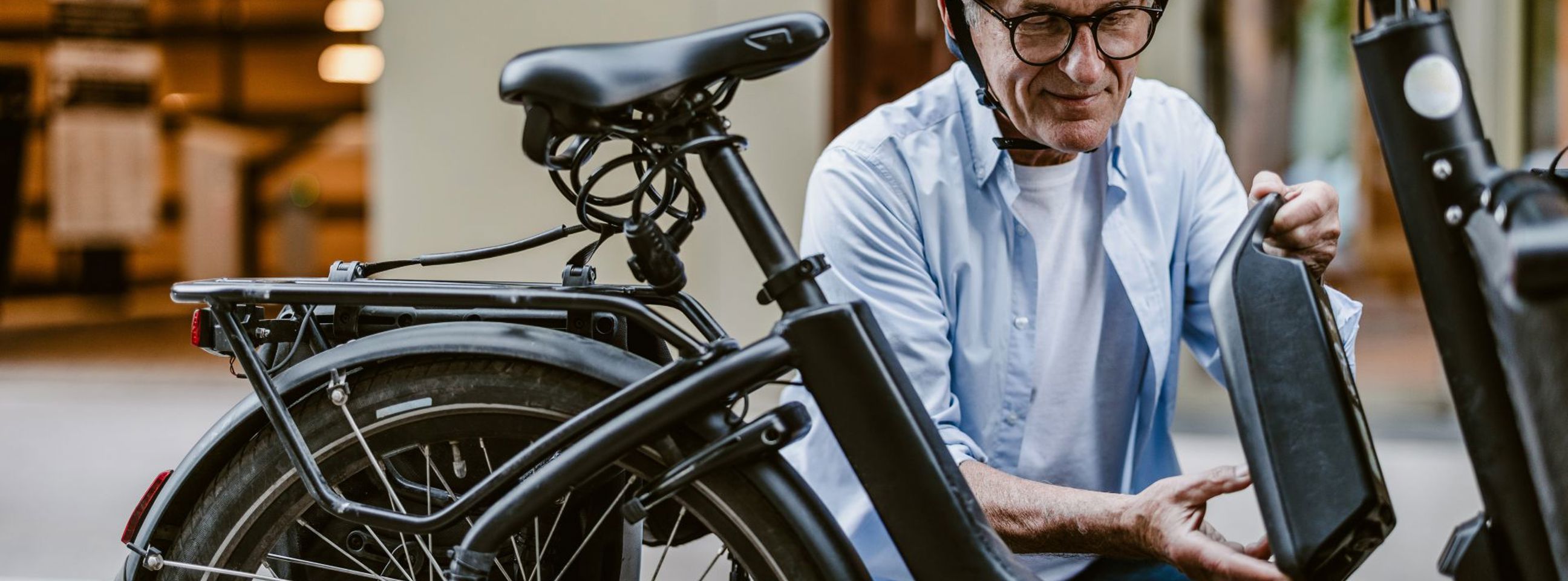 En mand med cykelhjelm er ved at afmontere batteriet på sin elcykel
