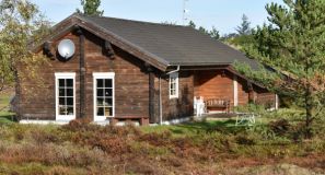 Sommerhus i naturen, med træer og buske omkring det.